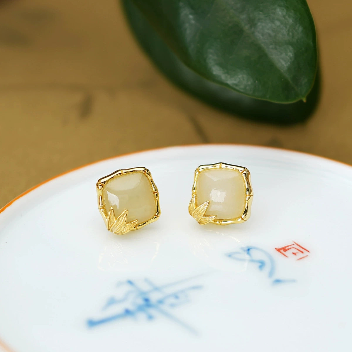 White Hetian jade stud earrings in S925 silver displayed on a ceramic dish