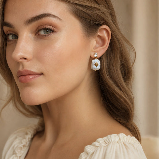 Woman wearing North Star square baroque pearl dangle earring with a crystal stud and gold-plated details