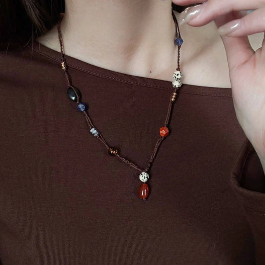 Mixed gemstone rope necklace styled on model with red stone pendant, black agate beads, and refined vintage design
