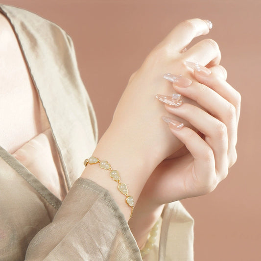 White Hetian jade hulu bracelet worn on wrist with minimalist neutral outfit.