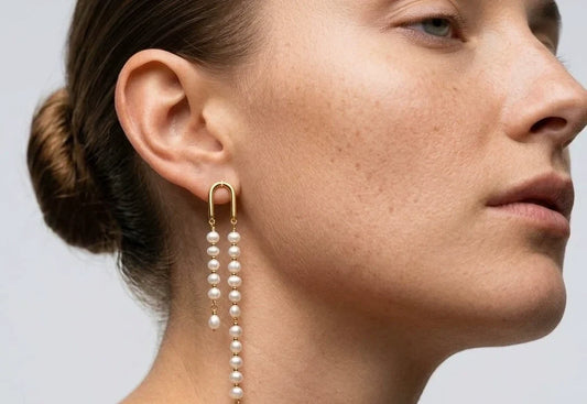 Woman with an updo wearing long asymmetric pearl tassel earrings