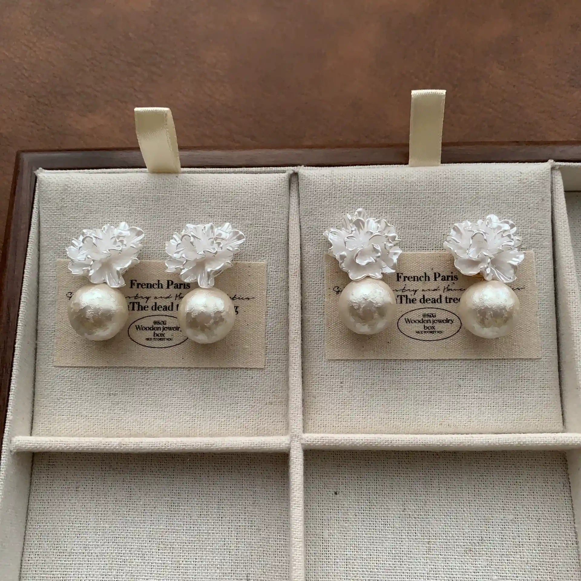Gold-tone and silver-tone 3D flower pearl earrings arranged in a jewelry box.