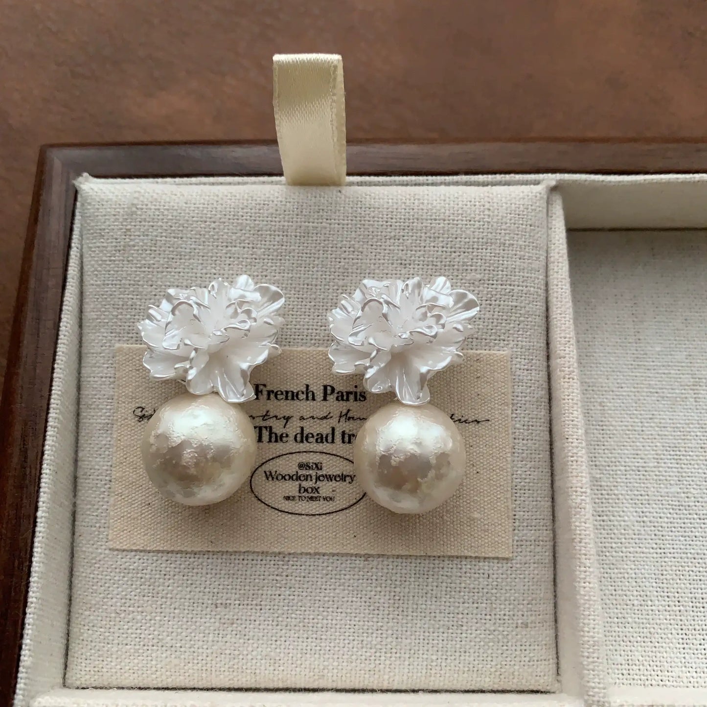 White floral pearl drop earrings with sculptural resin petals and luminous pearls.