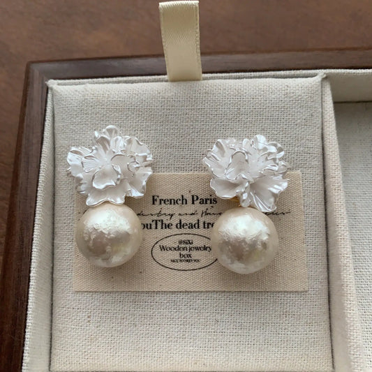 Close-up of 3D flower pearl earrings with white resin blooms and round pearl drops.