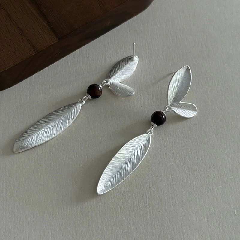 Side view of long silver leaf drop earrings with textured botanical details