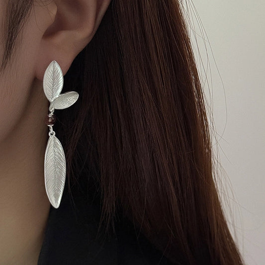 Model wearing long 925 sterling silver leaf earrings with a nature-inspired design