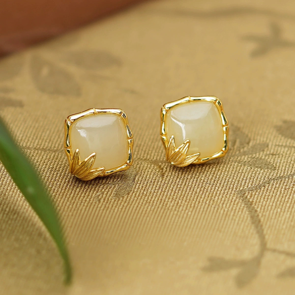 White Hetian jade square stud earrings with gold-tone bamboo and leaf details