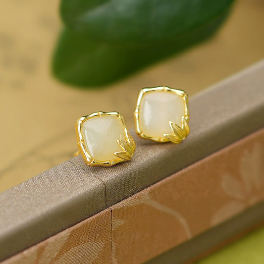 Minimalist white jade stud earrings displayed on a vintage jewelry box
