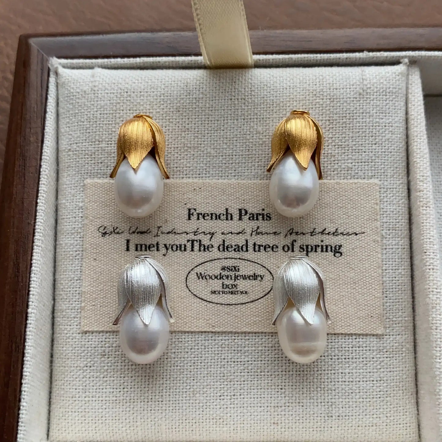 Gold and silver pearl bud stud earrings shown together in a jewelry box