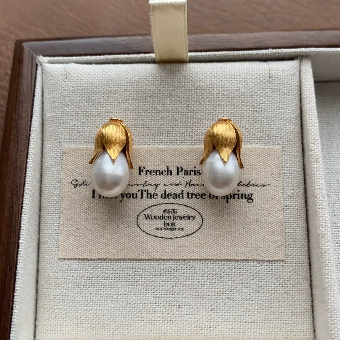 Front view of gold-plated baroque pearl stud earrings with botanical design