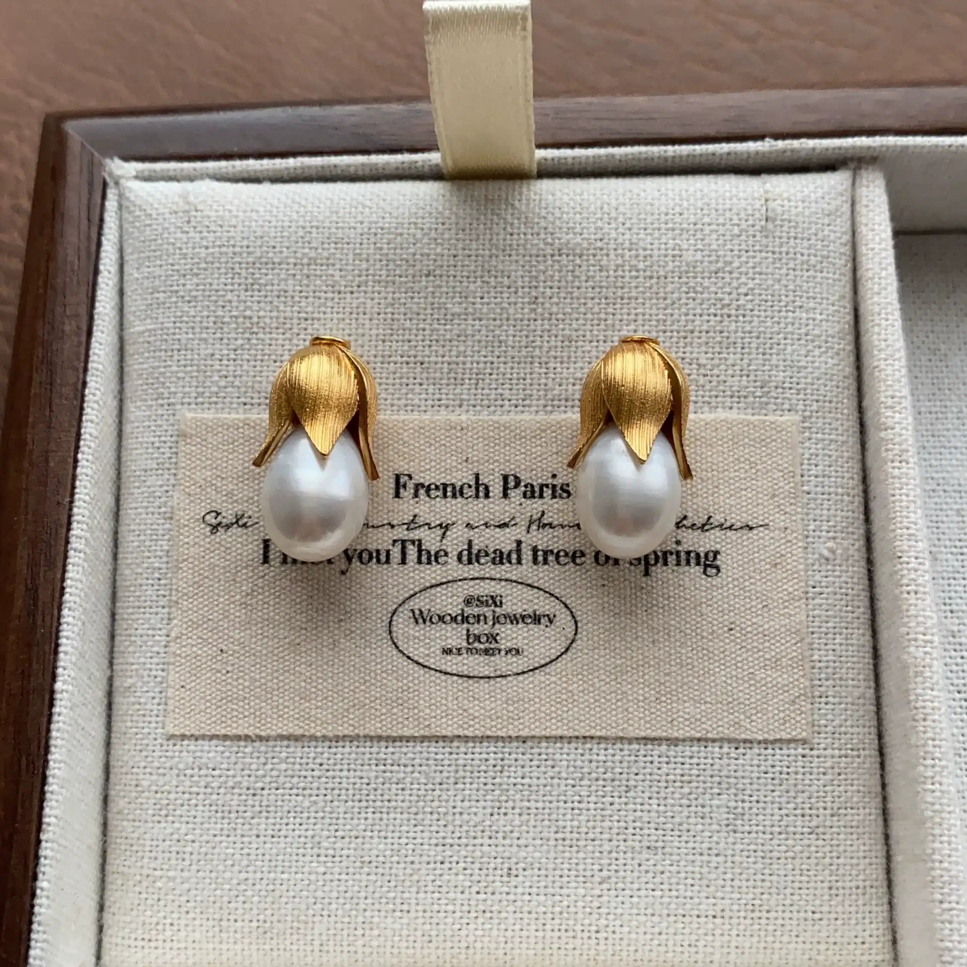 Front view of gold-plated baroque pearl stud earrings with botanical design