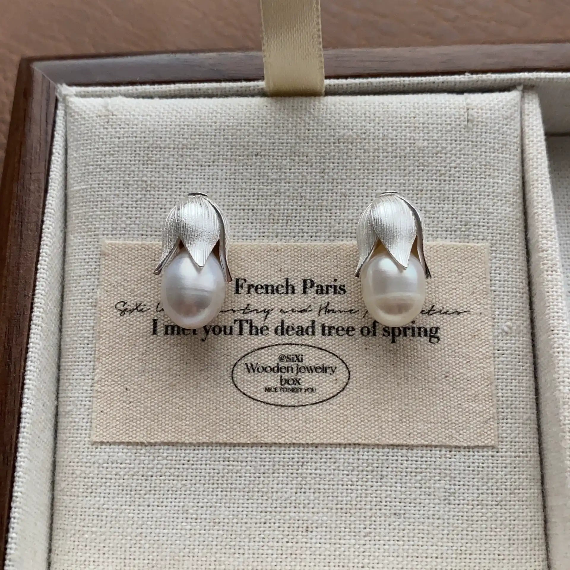 Front view of silver-plated baroque pearl bud earrings with teardrop pearls