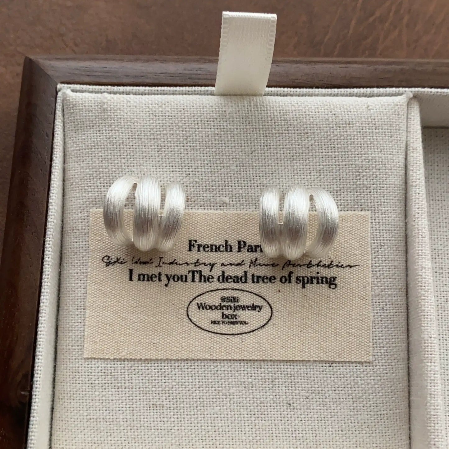 Silver-tone brushed triple hoop earrings with a compact sculptural C-shaped design.