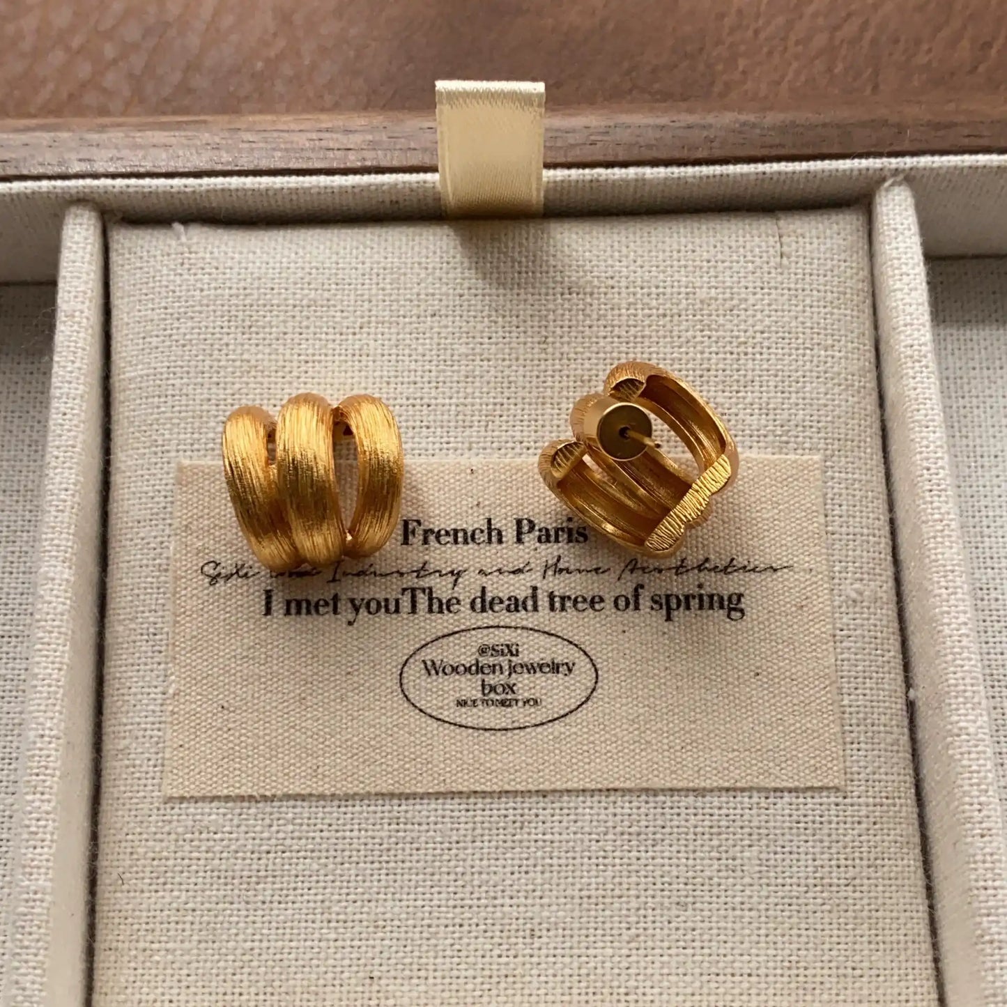 Back view of gold-tone triple band hoop earrings showing the stud fastening.