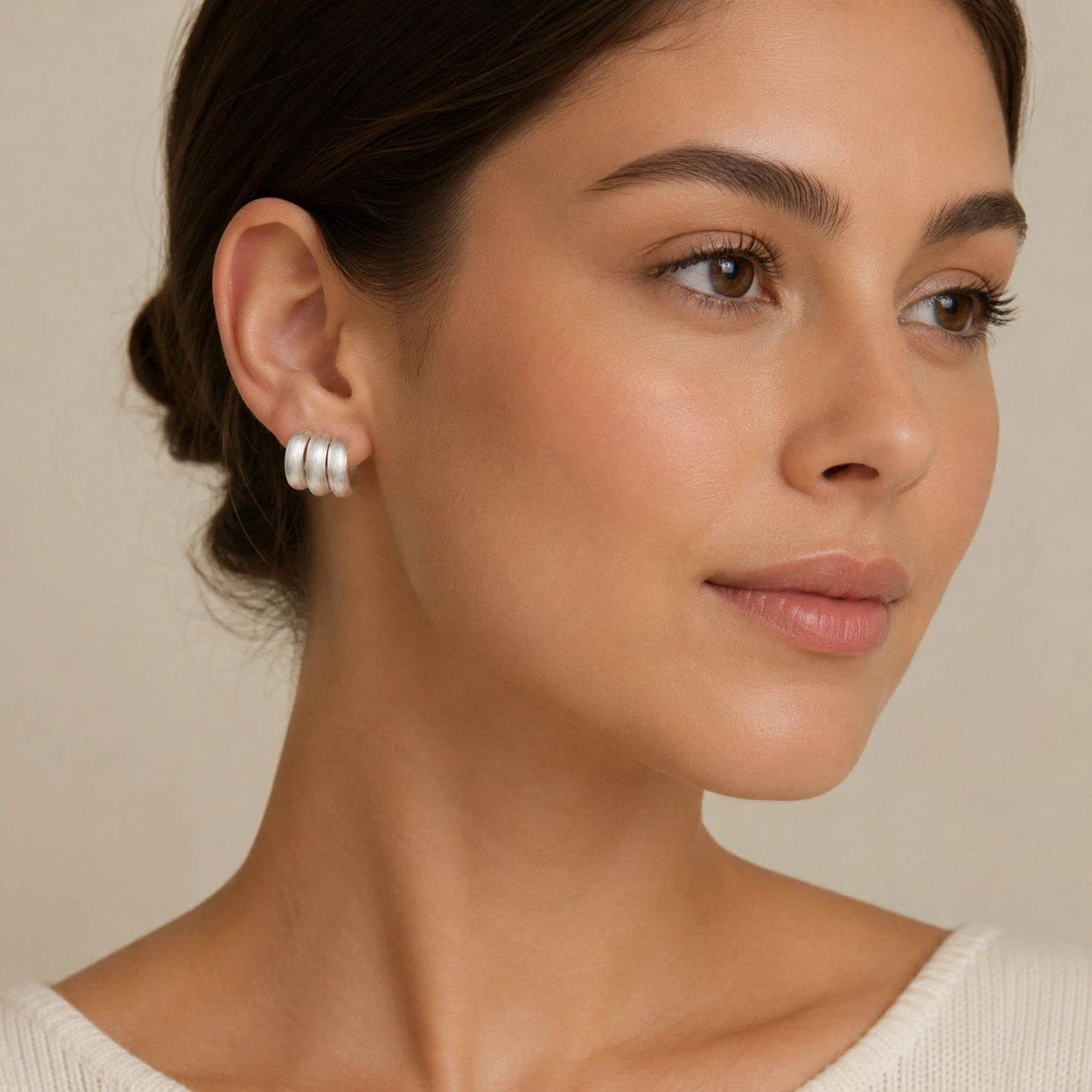 Model wearing silver-tone triple band earrings with a sleek low bun.