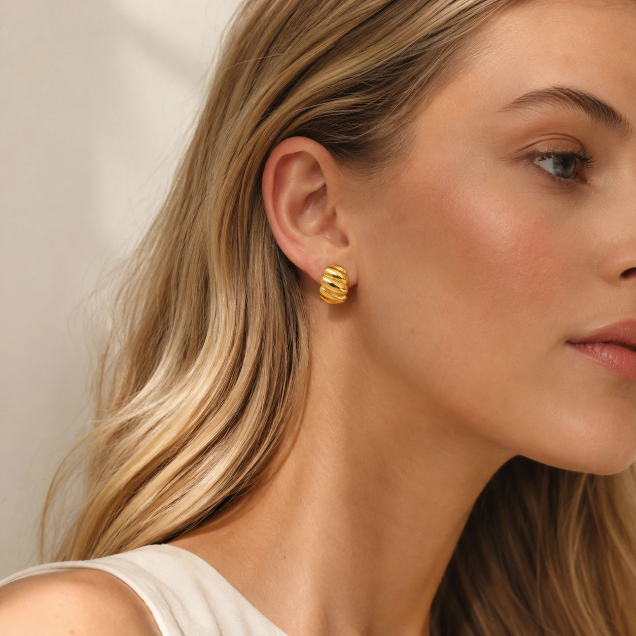 Model wearing gold tone croissant hoop earrings in an elegant everyday look