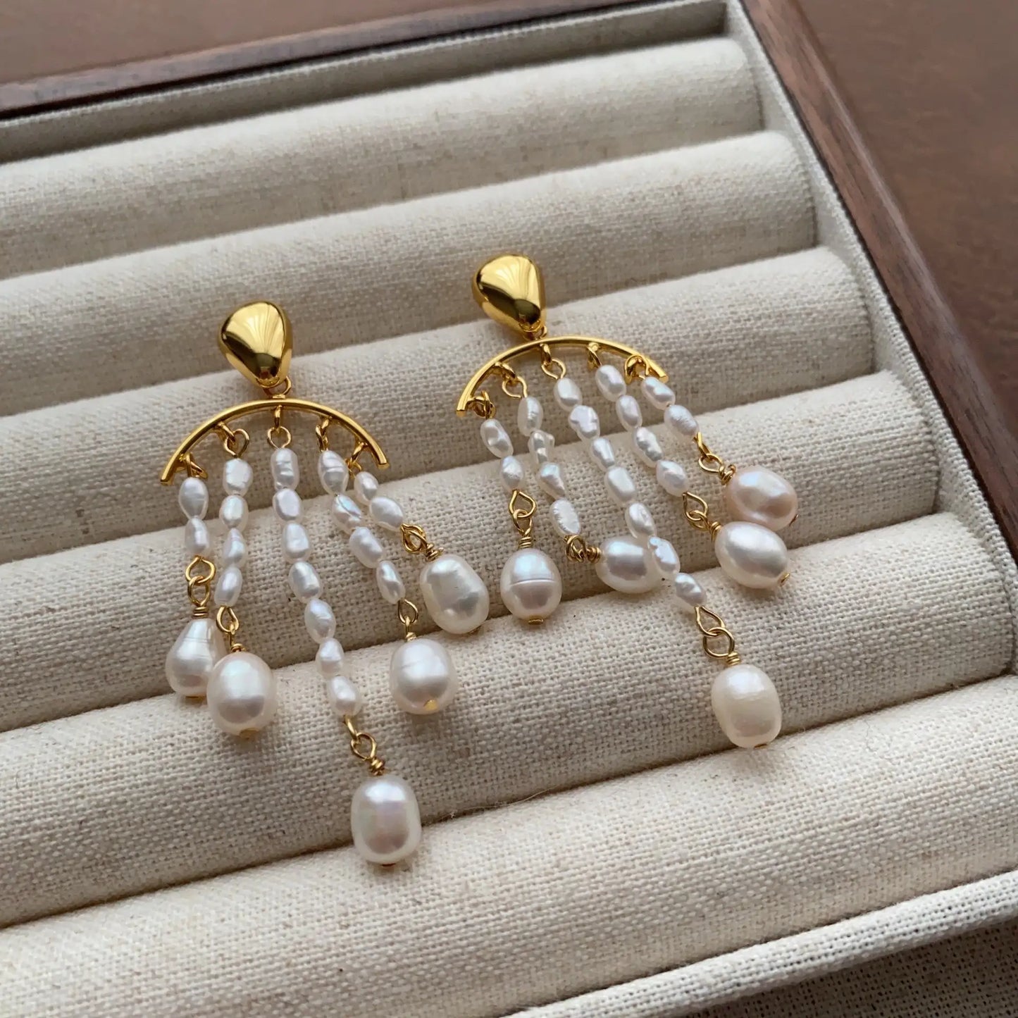 Pearl chandelier earrings arranged on a cream velvet jewelry display