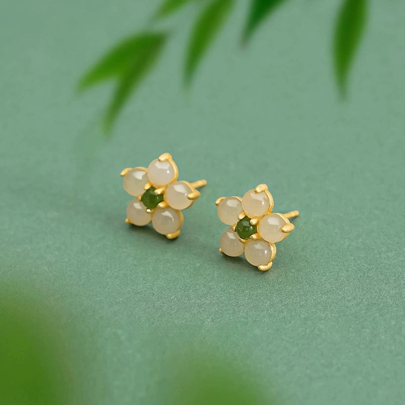 Hetian jade flower stud earrings with Biyu jade center on soft green background.