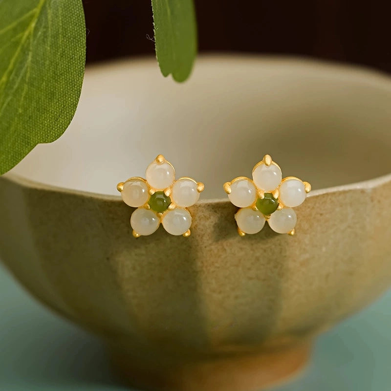 Natural Hetian jade floral stud earrings in 925 silver displayed beside ceramic bowl.