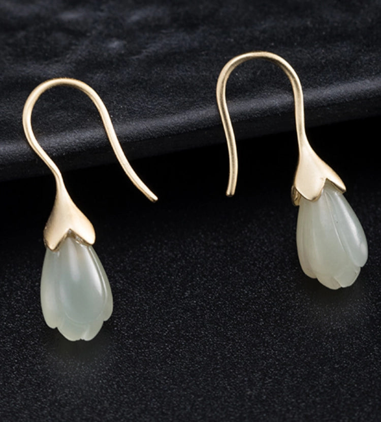 Close-up of Hetian jade lotus bud earrings with gold plated sterling silver floral setting.