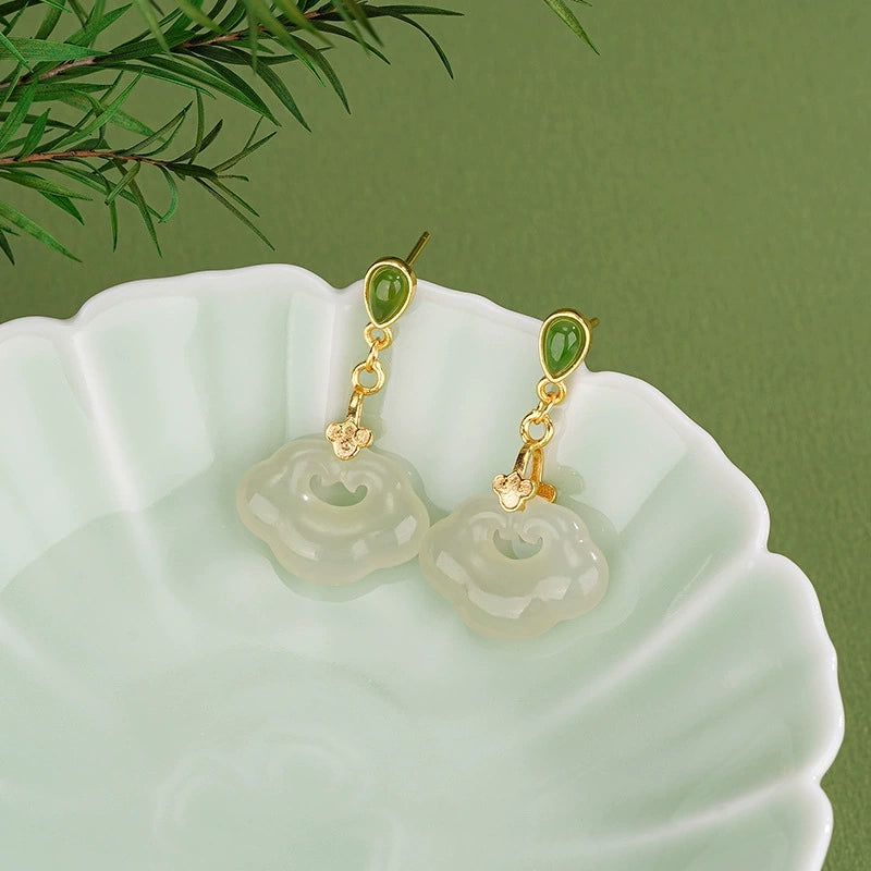 Hetian jade ruyi lock earrings with green jade studs displayed on pale green ceramic dish.