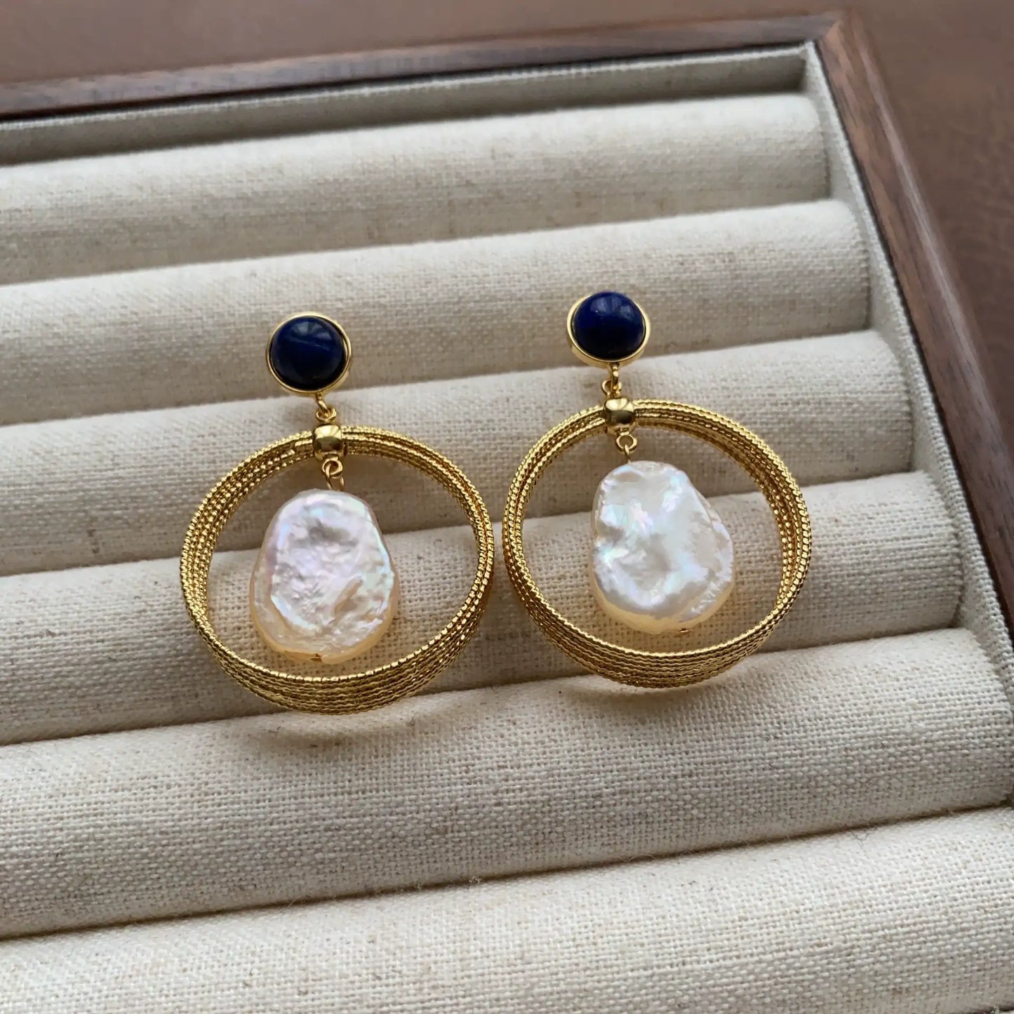 Lapis lazuli pearl hoop earrings arranged on a neutral velvet jewelry tray