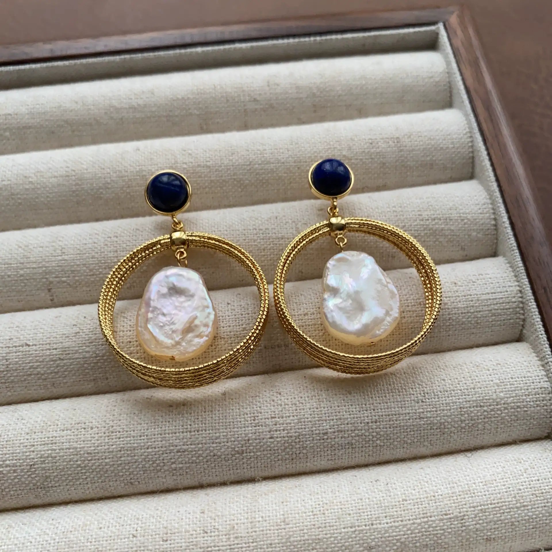 Lapis lazuli pearl hoop earrings arranged on a neutral velvet jewelry tray