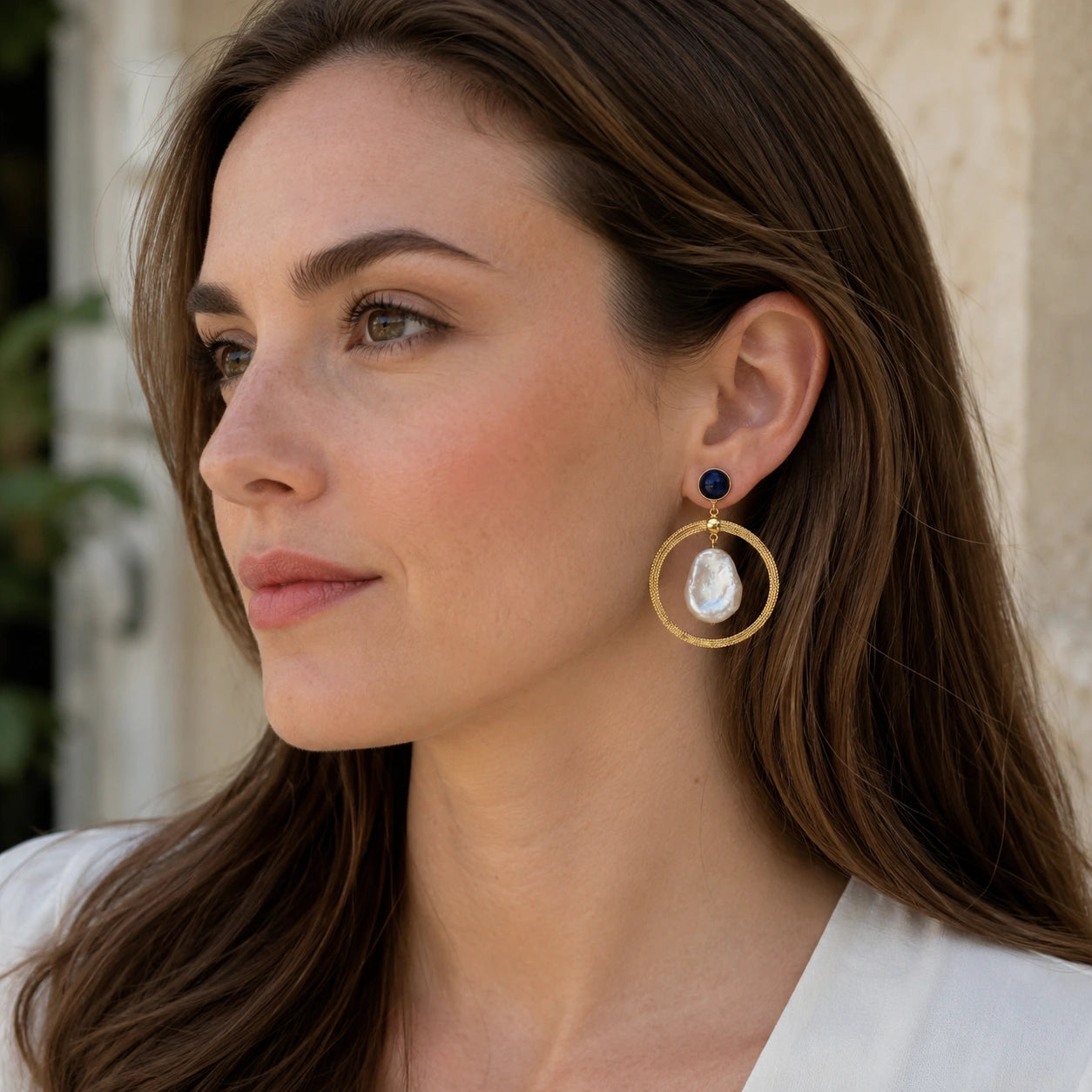 Model wearing lapis lazuli baroque pearl hoop earrings in an elegant natural setting