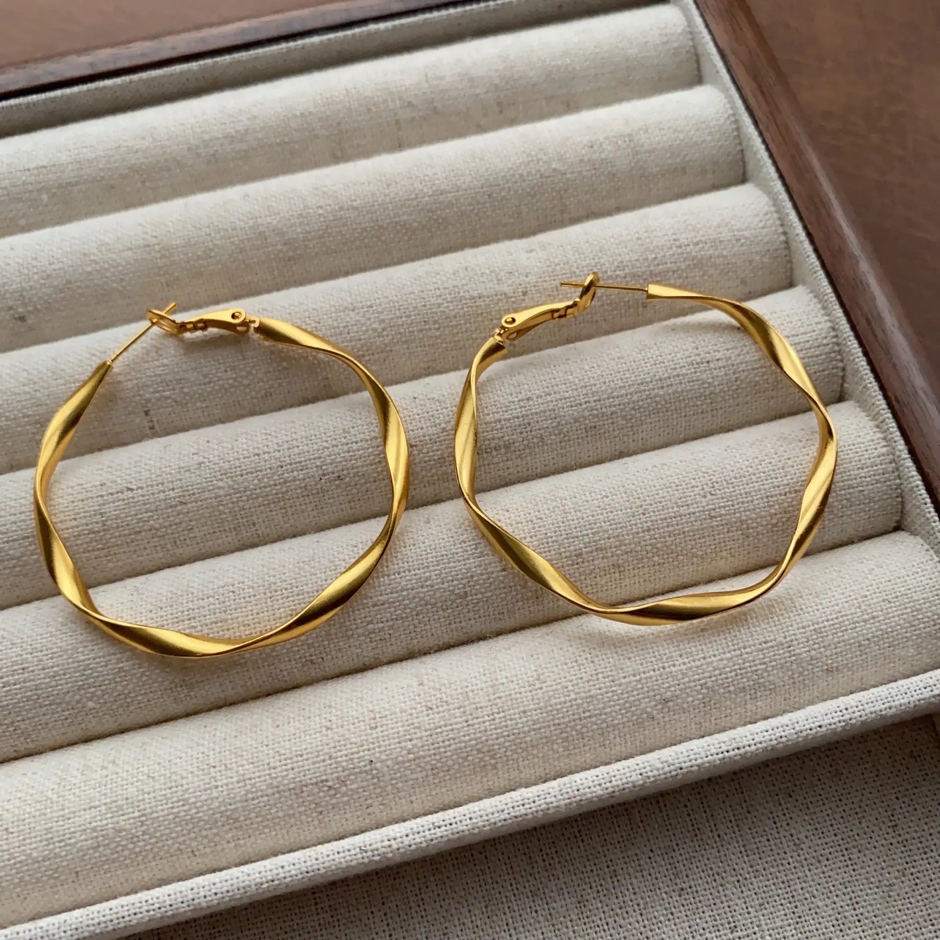 Close-up of gold wavy hoop earrings with a polished Möbius-inspired design