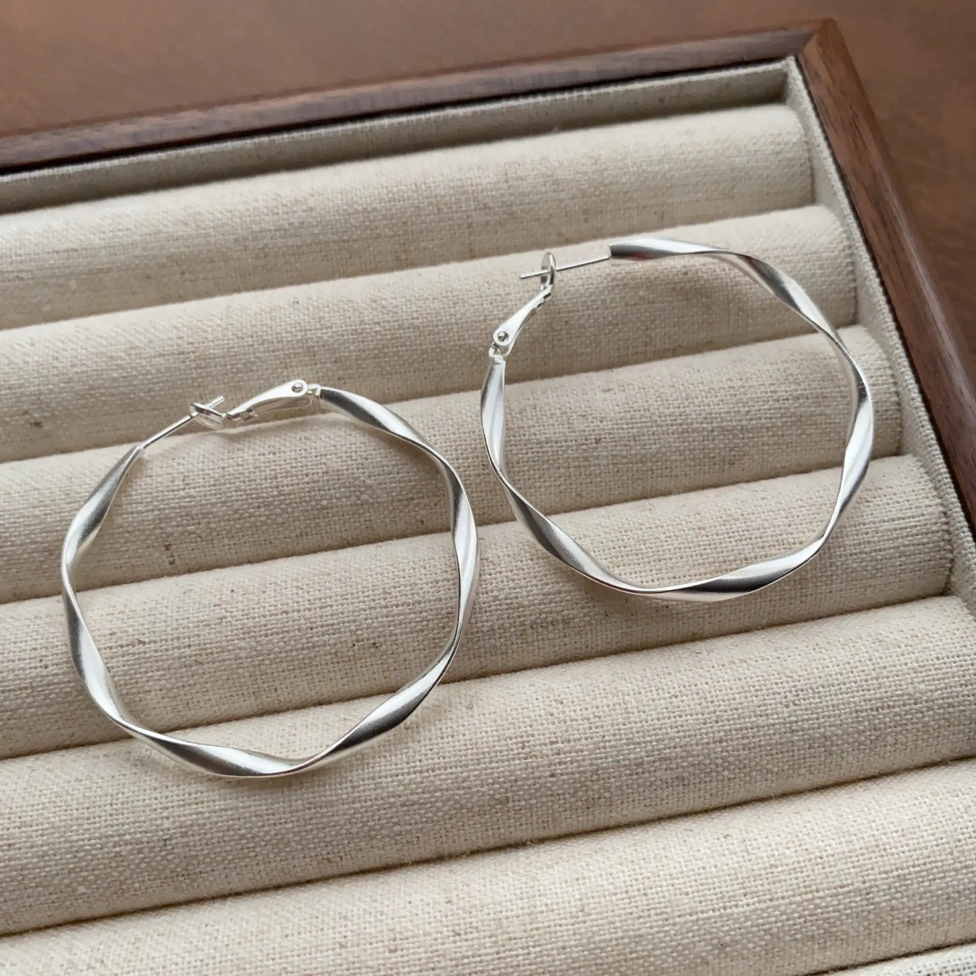 Close-up of silver geometric hoop earrings with a sleek twisted silhouette
