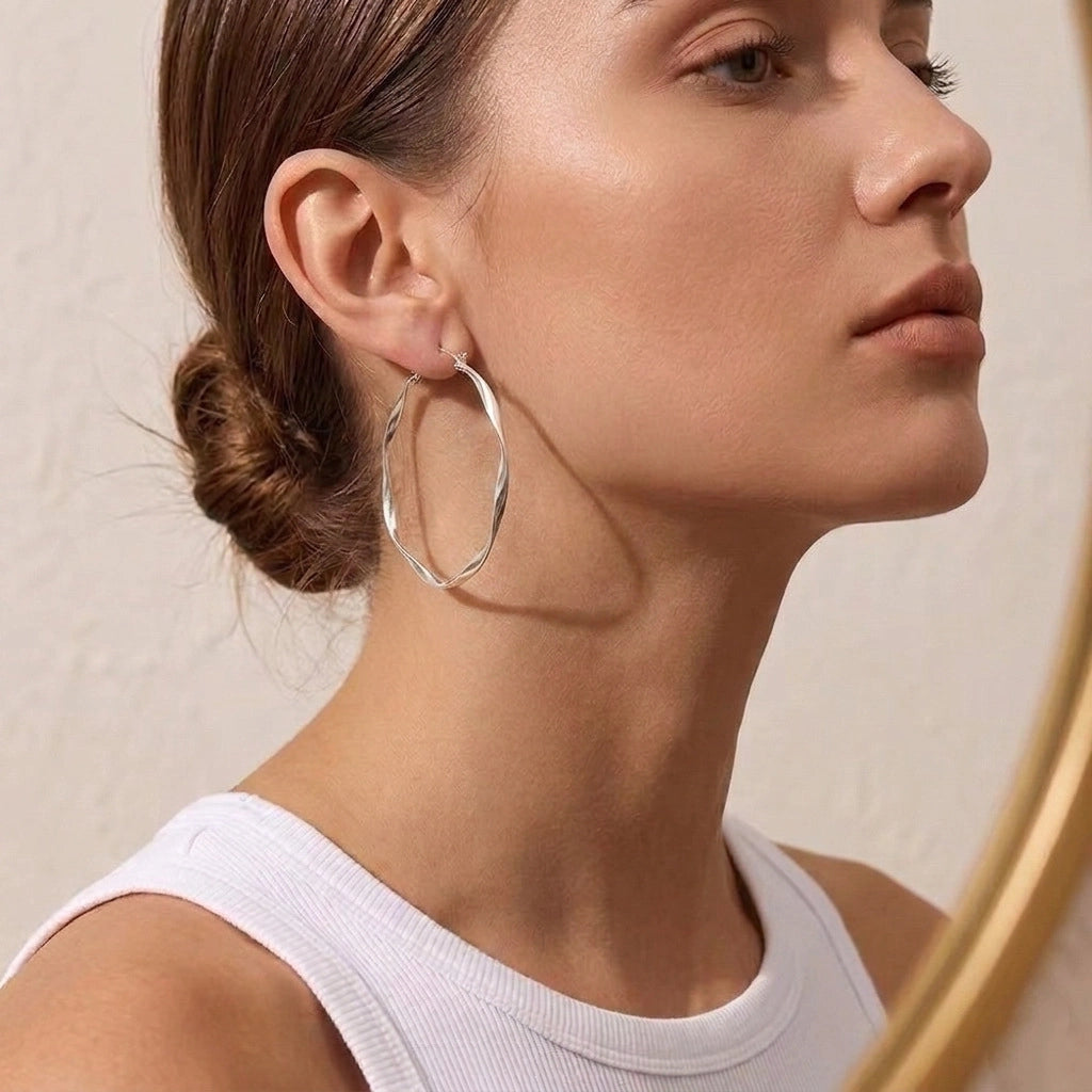 Model wearing silver twisted hoop earrings with minimalist modern styling