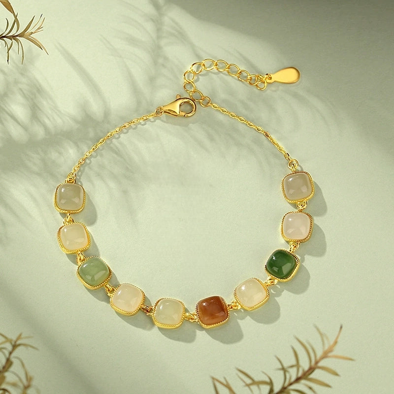 Multi-color Hetian jade bracelet with S925 extender chain laid on pale green background.