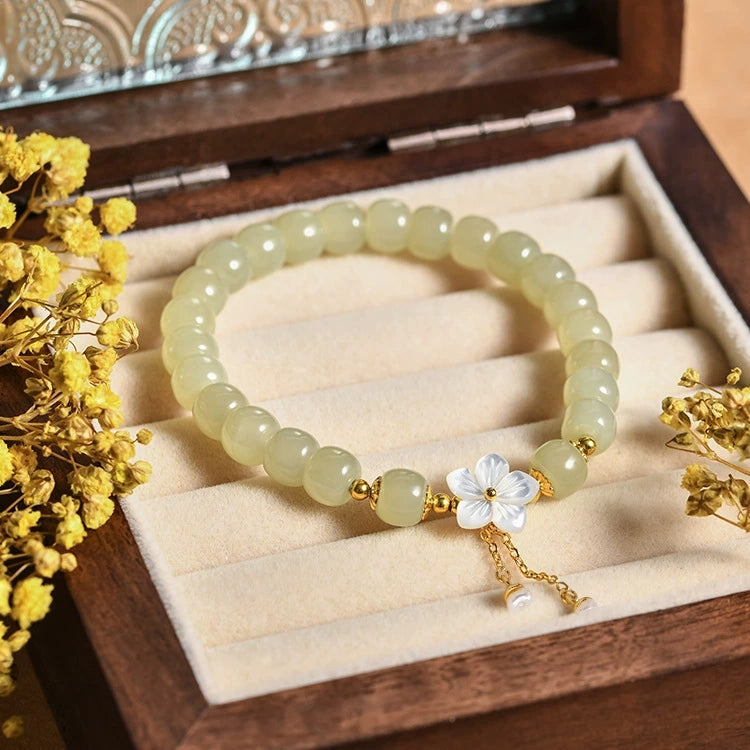 Natural Hetian jade beaded bracelet with shell sakura charm and pearl tassel in jewelry box.