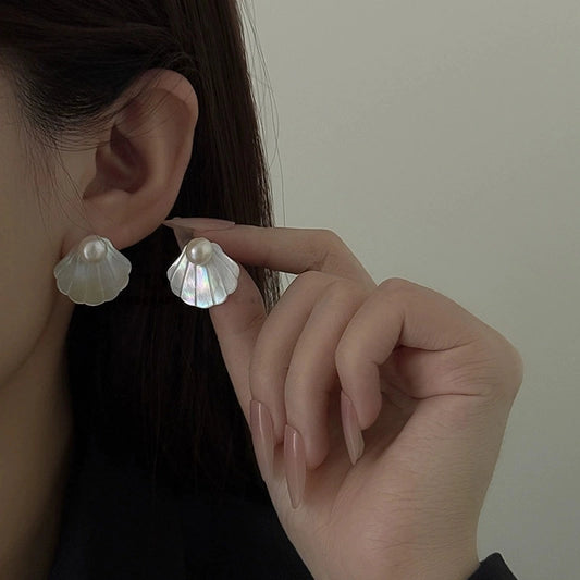 Model wearing natural mother-of-pearl seashell stud earrings with a soft coastal-inspired look.