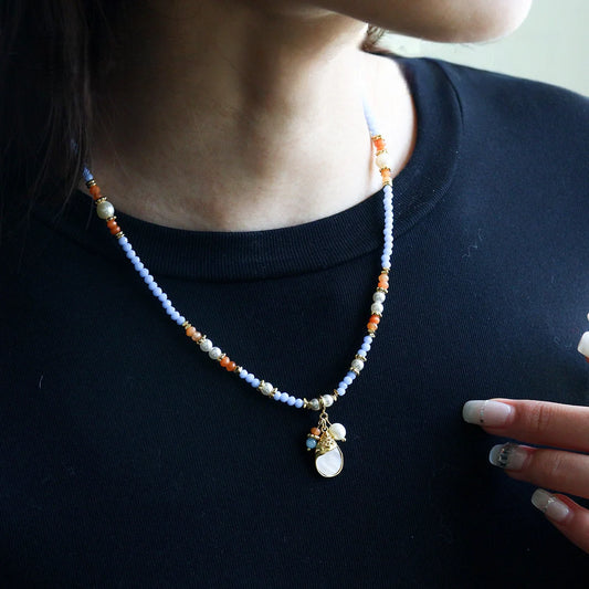 Pastel blue beaded shell pendant necklace styled on model with black top for everyday summer look