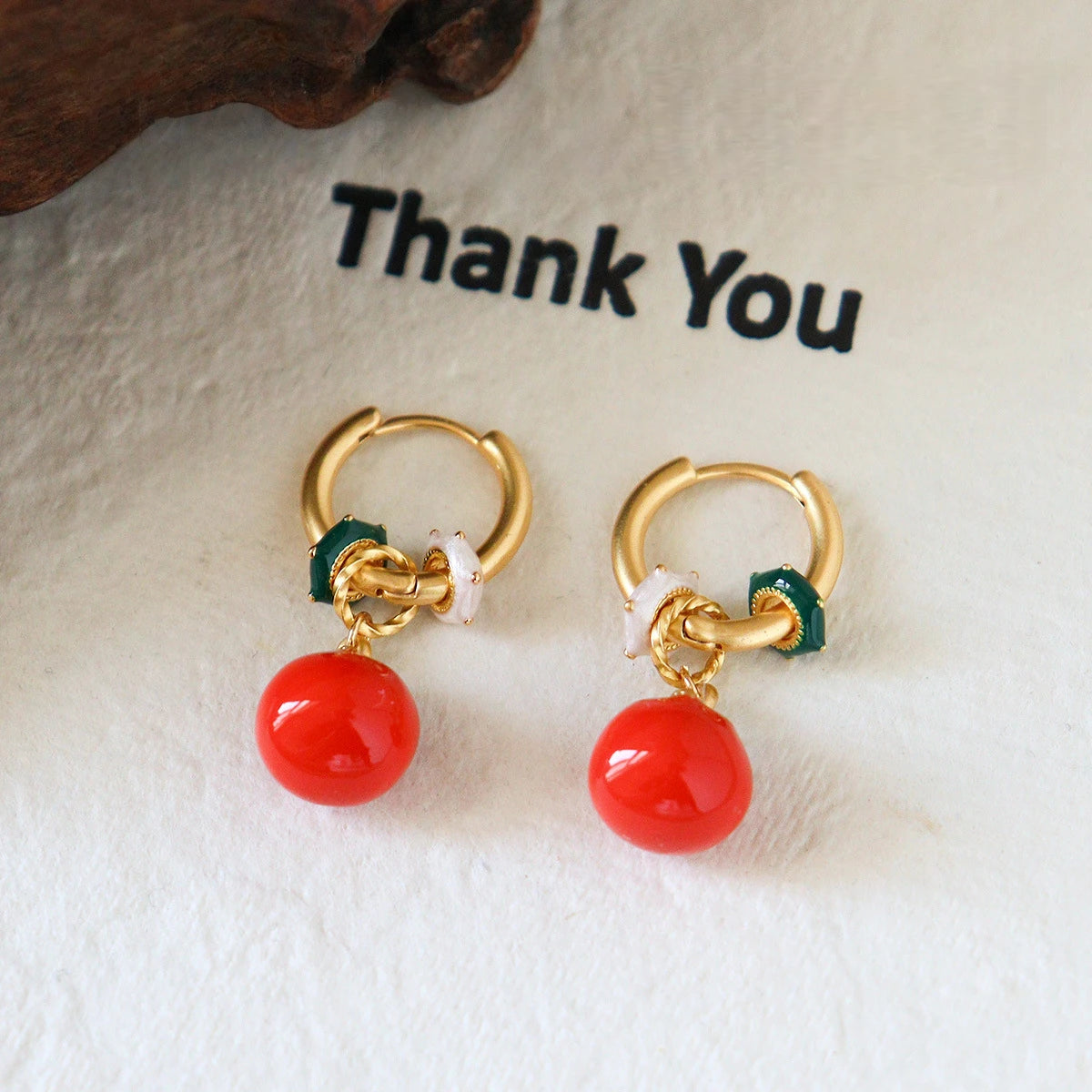French retro persimmon hoop earrings with bright red fruit pendants on a neutral background