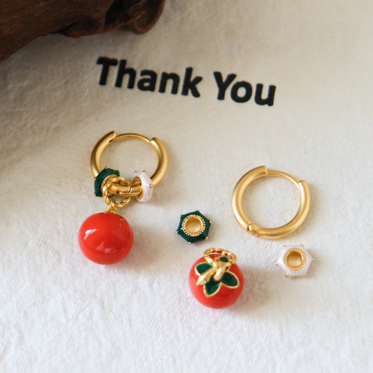 Detachable persimmon hoop earrings showing red fruit charms and gold tone brass components
