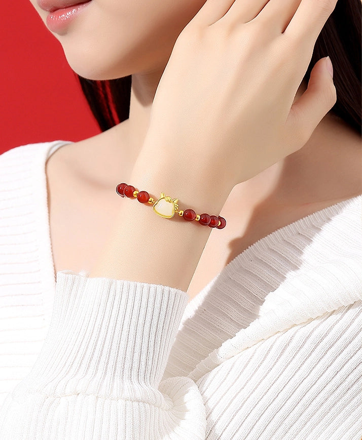 Eoela red agate white jade horse bracelet styled on wrist with elegant white sweater.