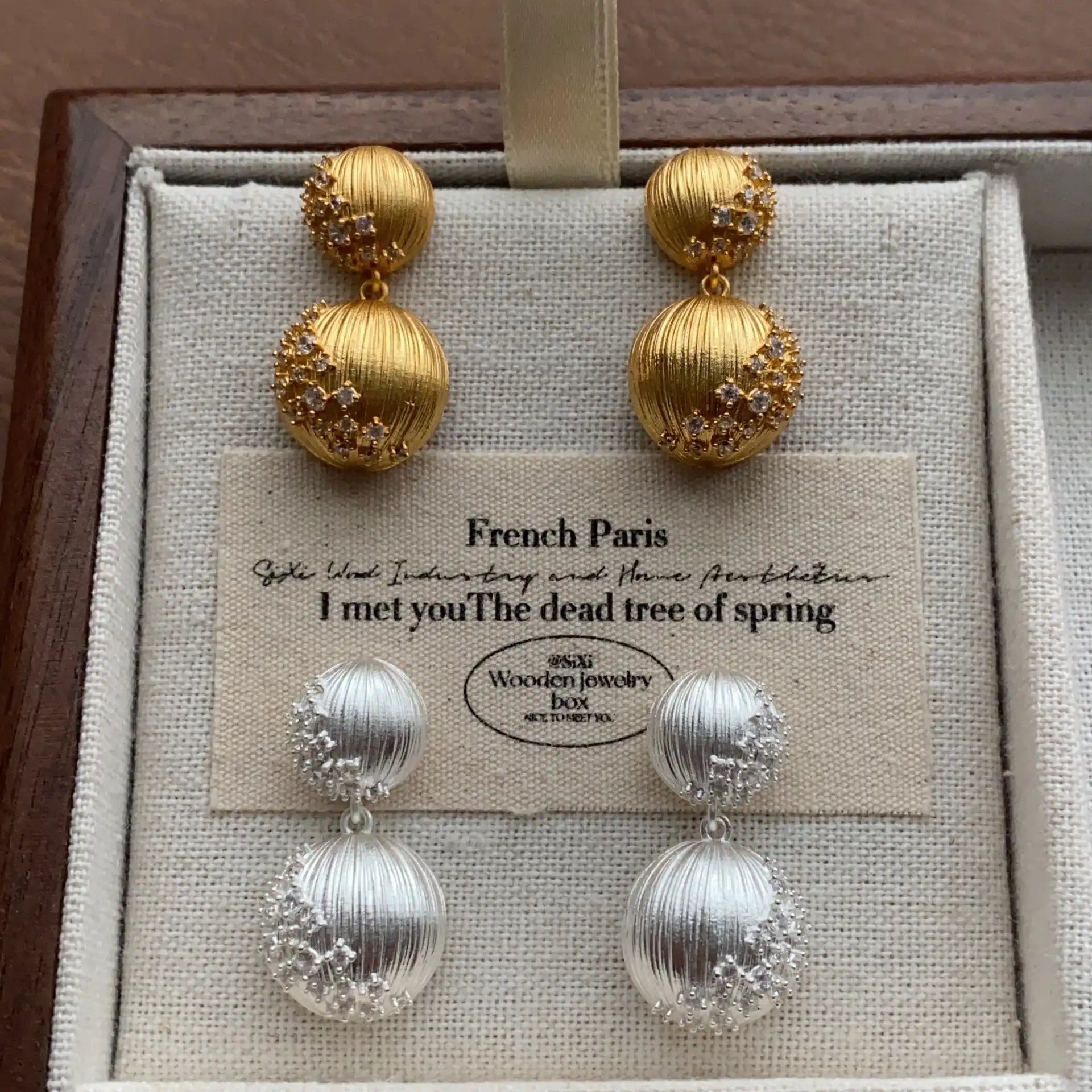 Gold and silver double orb earrings shown together on a fabric display card