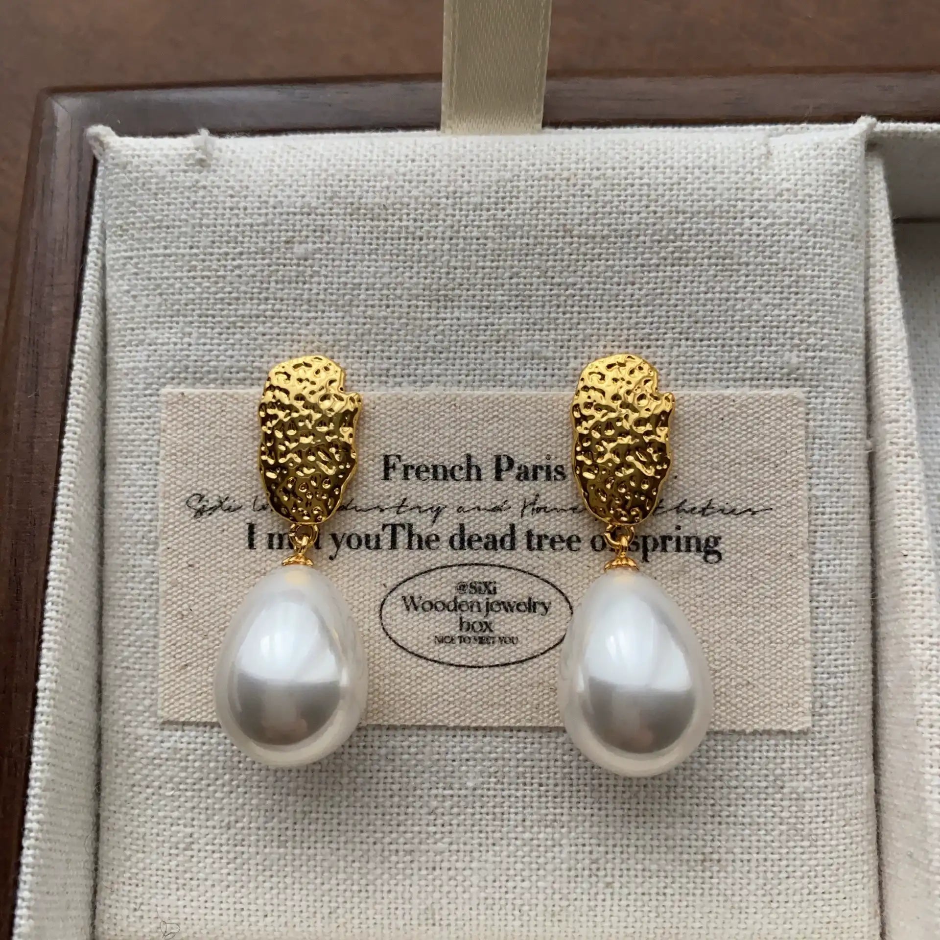 Front view of gold-plated pearl drop earrings with sculptural textured stud tops.