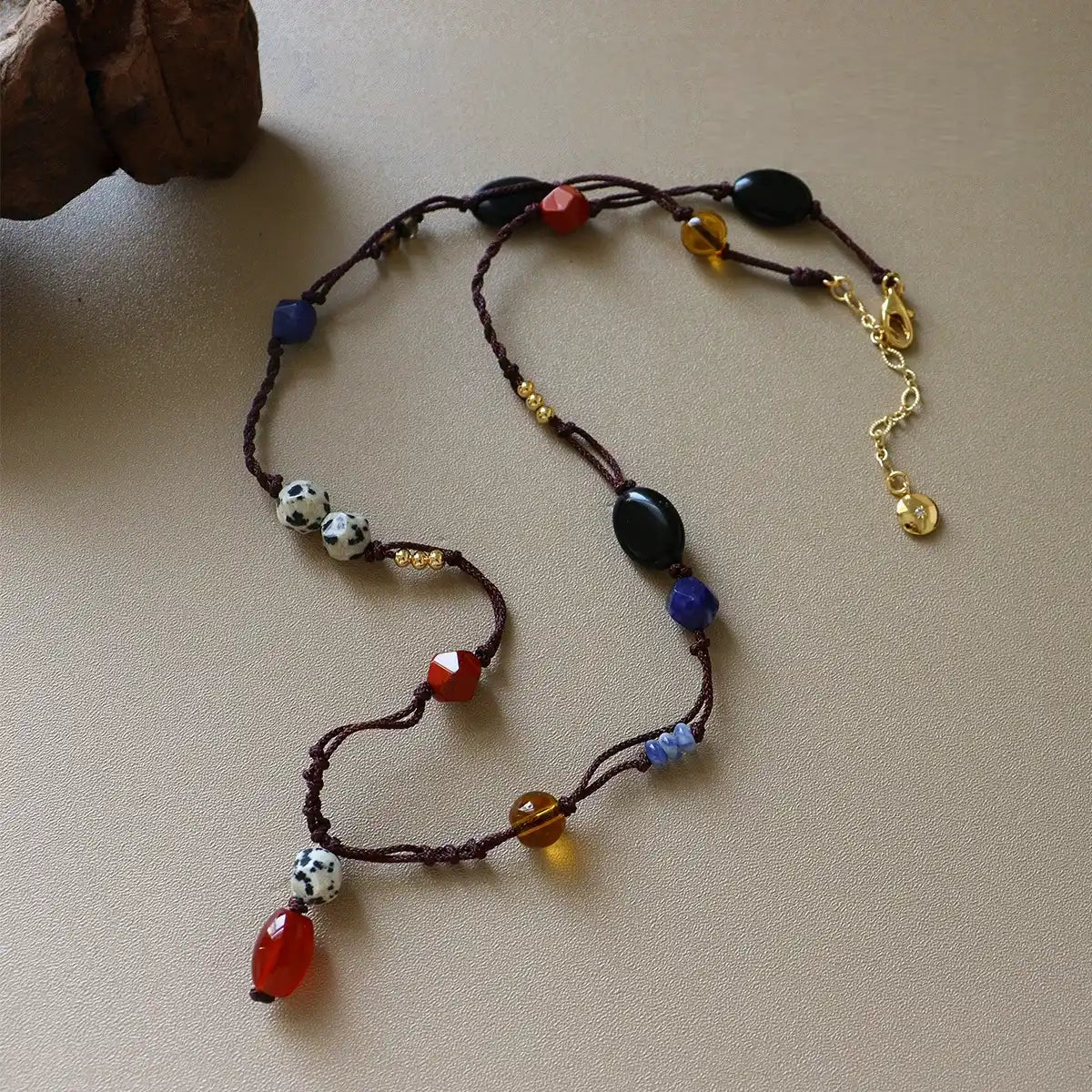 Vintage mixed gemstone rope necklace with dalmatian jasper, red stone, black agate, brass details, and brown cord
