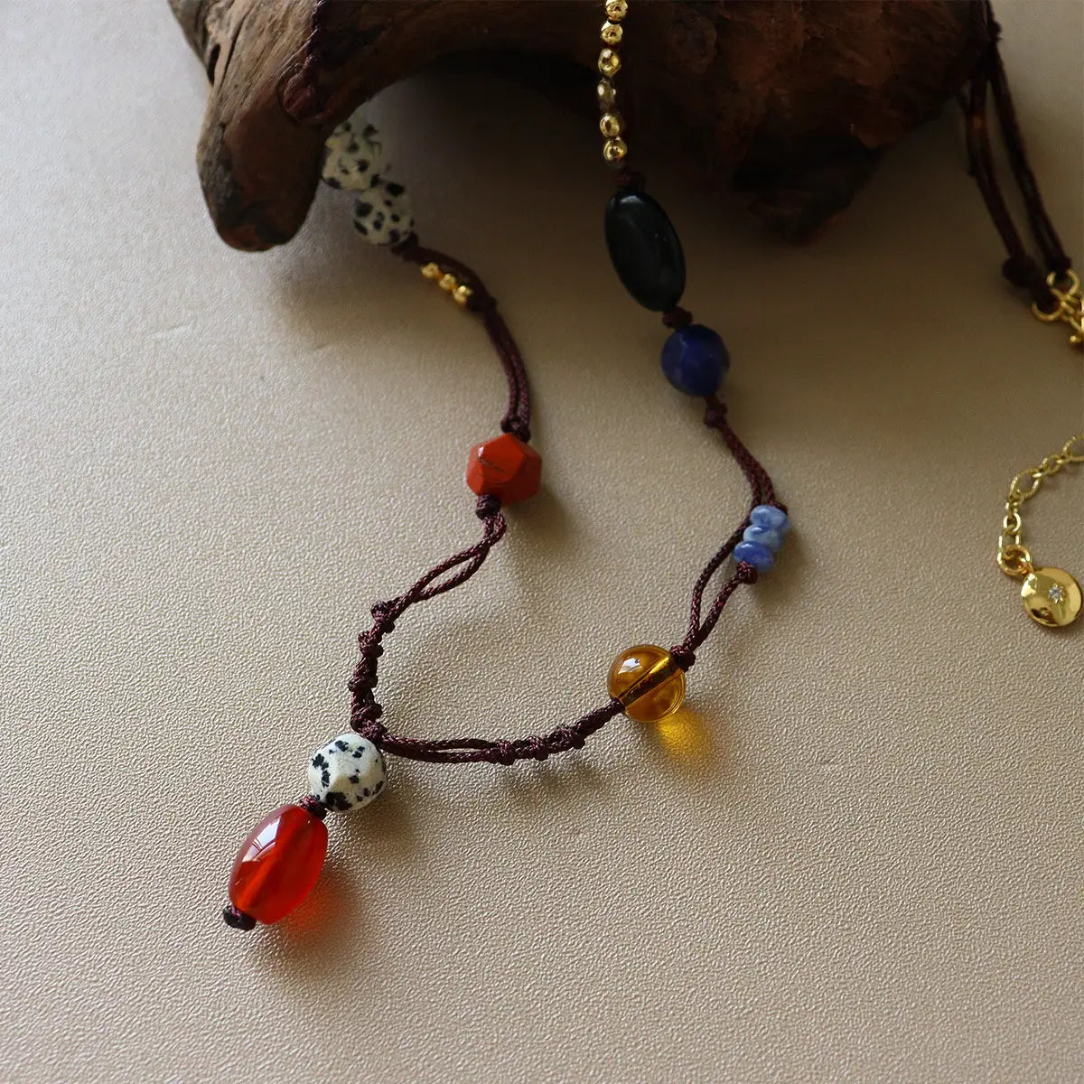 Close-up of natural stone rope necklace with red agate pendant, dalmatian jasper beads, black agate, and brass accents