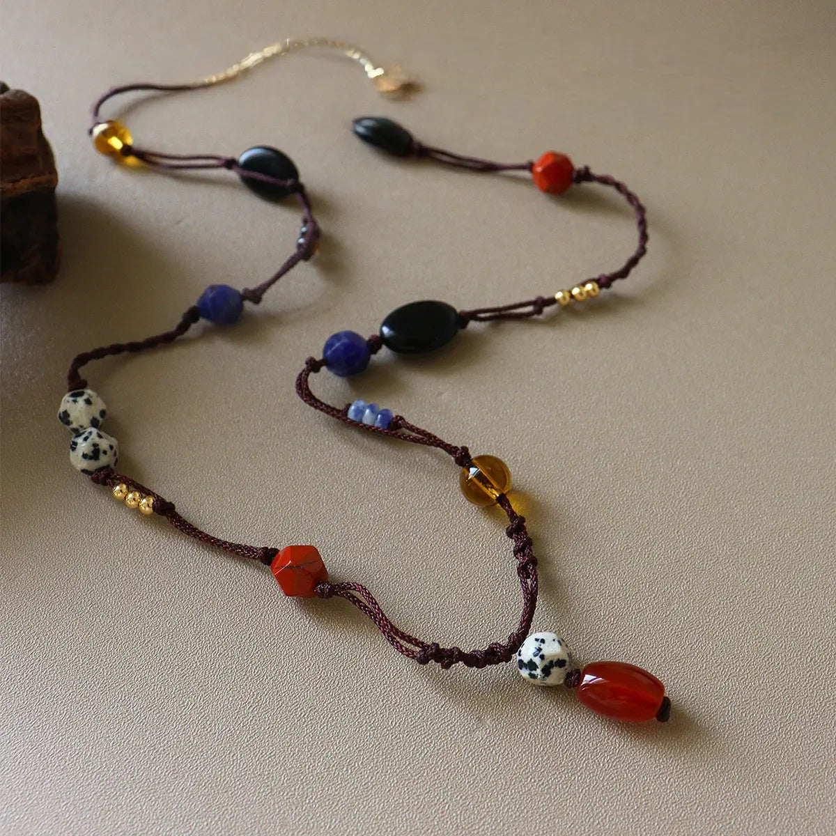 Colorful mixed gemstone strand necklace with red stone, black agate, dalmatian jasper, blue beads, and gold-tone chain