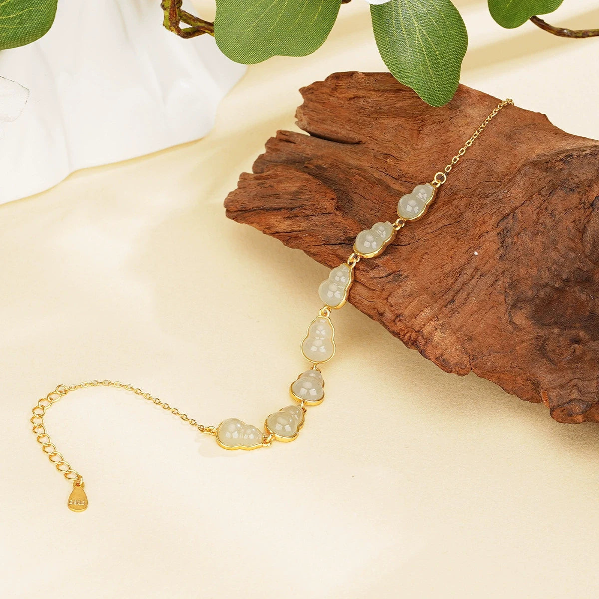 White Hetian jade hulu bracelet with S925 silver chain displayed on natural wood.